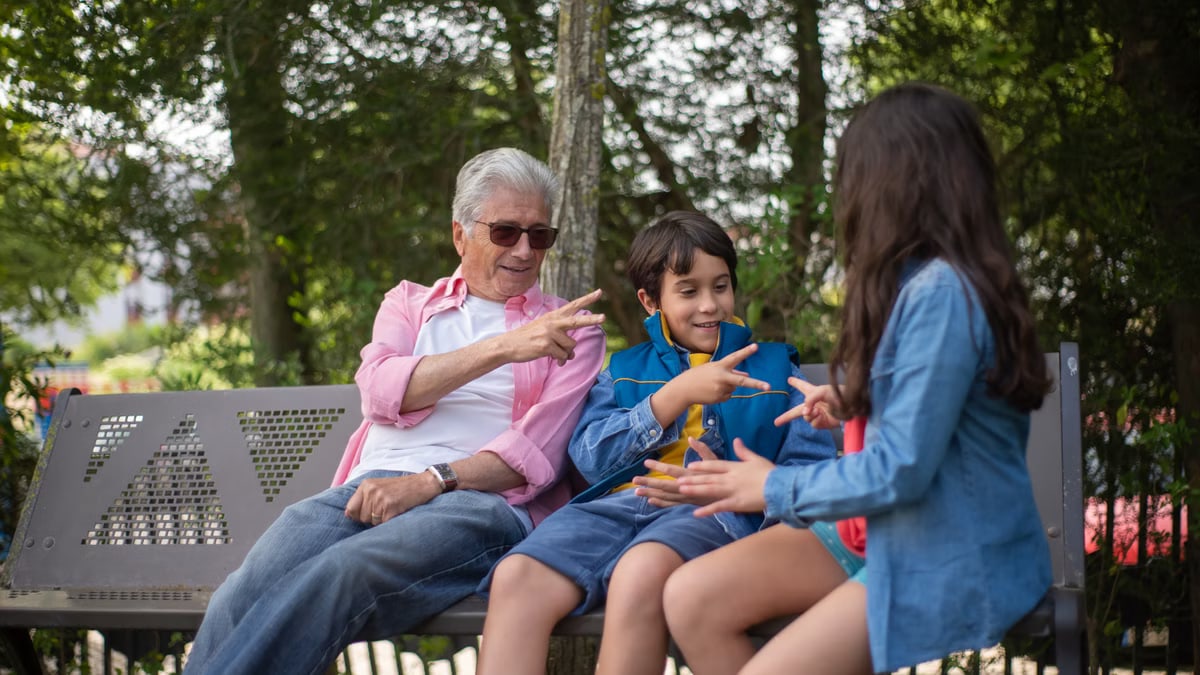 Grandfather and grandchildren bonding at a park bench in Portugal.